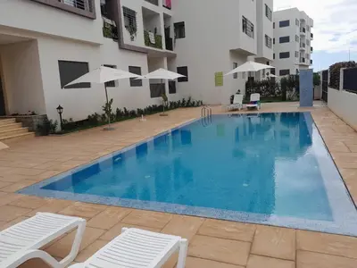a large blue swimming pool next to a building at Dar Lakbira Bouznika in Bouznika