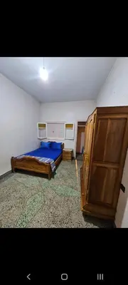 a bedroom with a bed and a wooden cabinet at Targuist in Settat