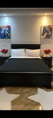 a bedroom with a large black bed with two flowers at Appartement meublé à louer in Rabat