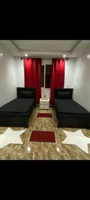 a living room with two beds and red curtains at Appartement meublé à louer in Rabat