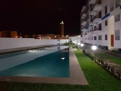 a swimming pool in front of a building at night at Bel appart les belles rives bouznika Couples non mariés non acceptés in Bouznika