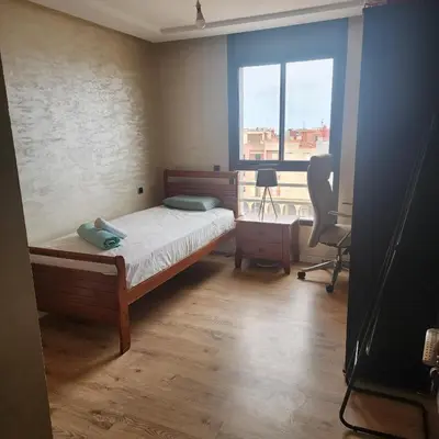 a bedroom with a bed and a desk and a window at Bel appart les belles rives bouznika Couples non mariés non acceptés in Bouznika