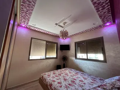 a bedroom with a bed and purple lights at Skhirat apartment in Skhirat
