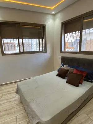 a bedroom with a large bed with two windows at Sunny Cozy House Close to the Beach in Bouznika