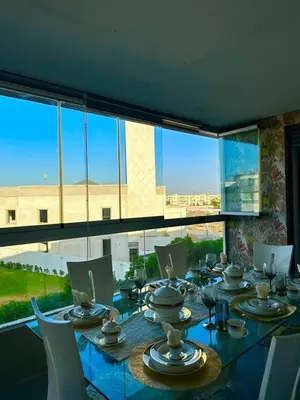 a dining room with a table and a large window at Appartement meublé à louer à dar bouazza in Tamaris