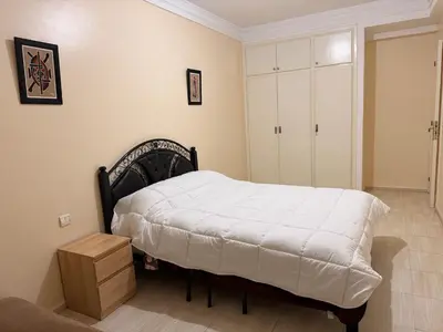 a bedroom with a bed with a white blanket on it at Agdal Central Spacious 2BR with Terrace in Rabat