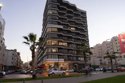 a tall building with cars parked in a city at Luxury Studio Corniche near H2 Area in Casablanca