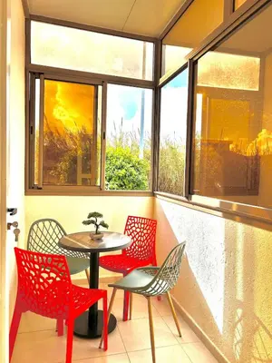 a patio with red chairs and a table in front of a window at Chic 2-bedroom apartment, pool and beach 5 min away in Mohammedia