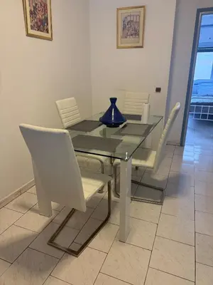 a glass table with white chairs and a blue vase on it at Spacious apartment in Agdal, close to everything in Rabat