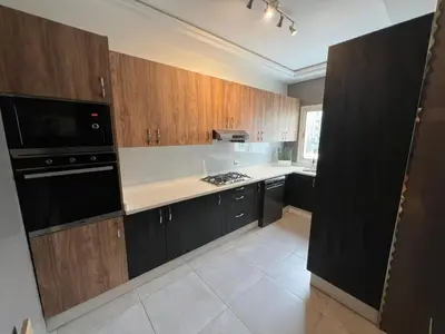 a kitchen with wooden cabinets and a black appliance at Appartement 2 chambres in Casablanca
