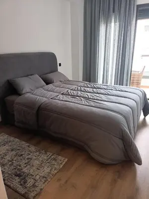 a large bed in a bedroom with a large window at Appartement haut standing piscine et fitness in Mohammedia