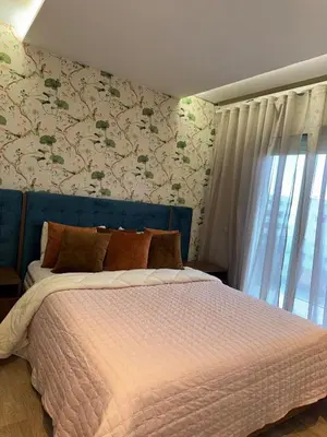 a bed with a blue head board in a bedroom at Luxury SeaView Apartment 2 Minutes From Beachfront in Rabat