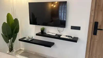 a television hanging on a wall with black shelves at Casablanca Luxe studio in Casablanca