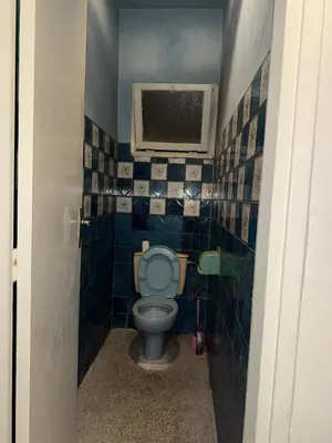 a bathroom with a toilet with a blue tiled wall at House for rent in Agdal in Rabat