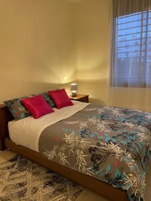 a bedroom with a bed with red pillows and a window at Beautiful 3 Bedroom in Heart of Hay Riad in Rabat