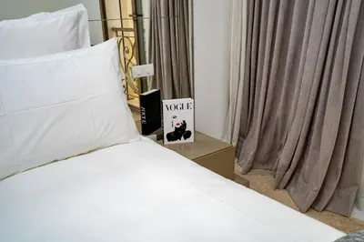a bed with white sheets and a book next to a window at Appartement cosy & chic Triangle d'or in Casablanca