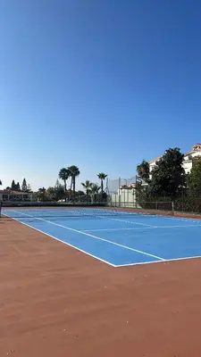a tennis court with a blue tennis court at Spacious beach escape villa with pool & play areas in Mansouria