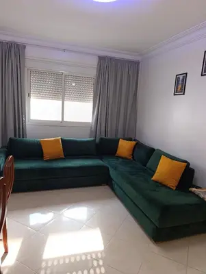 a living room with a green couch with yellow pillows at Carino Solare ben ordinato in Dar Ben Abdallah Ben Dehbi