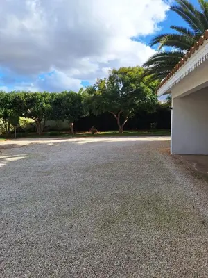 a driveway with a building and trees in the background at Chambre indépendante dans jardin calme avec vue mer Skhirat in Skhirat