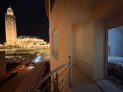 a balcony of a building with a clock tower at night at Appartement avec vue sur monument emblématique Hassan II in Casablanca