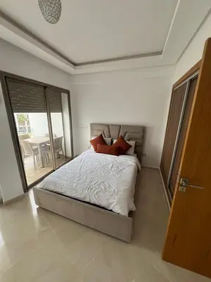 a bedroom with a bed and a sliding glass door at Palm Pool View Apartment - Bouznika in Bouznika