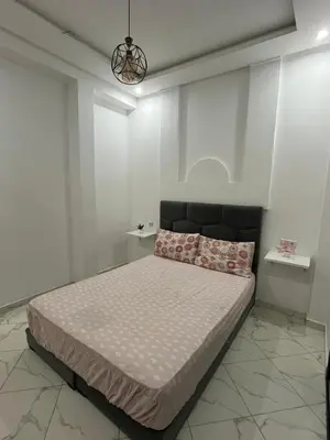 a bedroom with a large bed with white walls at Charming appartement next to the airport in Deroua
