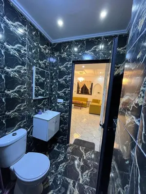 a bathroom with a toilet and a living room at Charming appartement next to the airport in Deroua