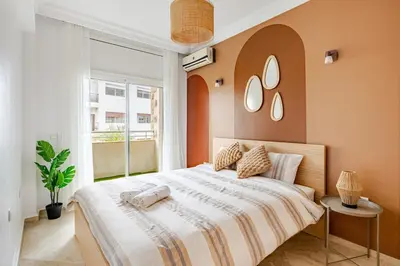 a bedroom with a large bed with two mirrors on the wall at Spacious, 2 BDR, Balcony, AC, Parking, Fiber Optic - Agdal in Rabat