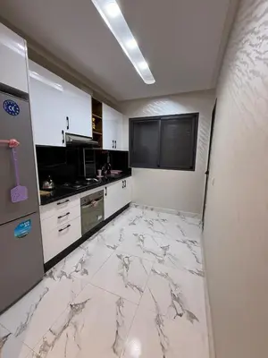a kitchen with white marble flooring in a room at Comfortable 2-bedroom apartment, beach within walking distance in Bouznika