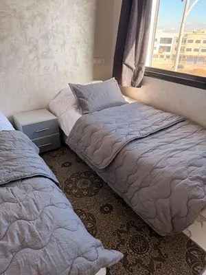 a bedroom with two beds next to a window at Comfortable 2-bedroom apartment, beach within walking distance in Bouznika
