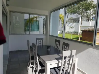 a dining room with a table and chairs and windows at Appartement pied sur mer in Mohammedia