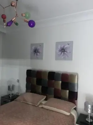 a bedroom with a bed with a couch and pictures on the wall at Appartement pied sur mer in Mohammedia