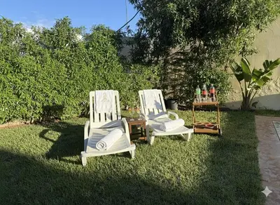 two white chairs sitting on the grass in a yard at Grande villa sécurisée piscine privée in Dar Bouazza