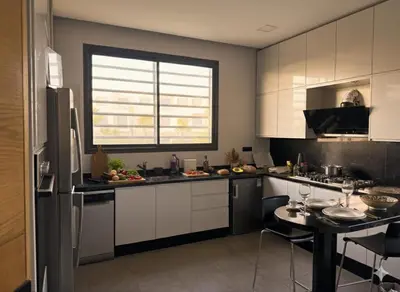 a kitchen with white cabinets and a table in it at Grande villa sécurisée piscine privée in Dar Bouazza
