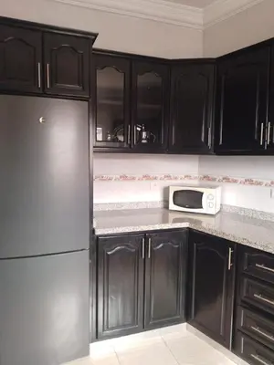 a kitchen with black cabinets and a white microwave at Joli appartement bien équipé-Casablanca in Casablanca