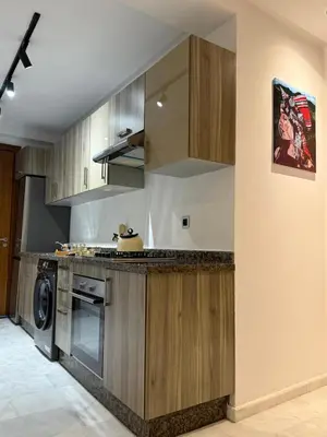 a kitchen with wooden cabinets and a washer and dryer at Élégant studio moderne Anoual Maarif Casablanca parfaitement équipé in Casablanca
