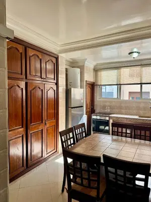 a kitchen with a table and chairs and a kitchen with a refrigerator at Spacious athène apartment in Maarif