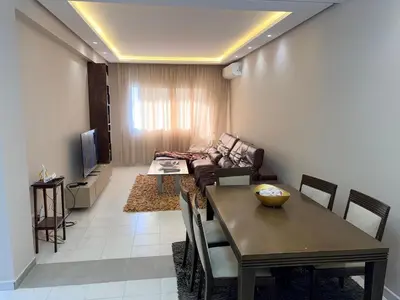a living room with a table and a couch at Très joli appartement très calme, très agréables pour un séjour en famille au haut Agdal Rabat in Rabat