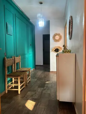 a kitchen with green cabinets and a table and a refrigerator at Cozy Apartement next to the airport in Deroua