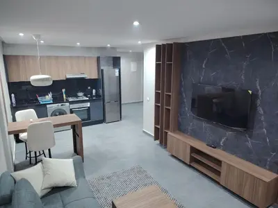 a living room with a large television and a kitchen at Studio luxueux in Roches Noires
