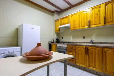 a kitchen with wooden cabinets and a vase on a table at Bel appartement piscine & plage - Mohammedia in Mohammedia