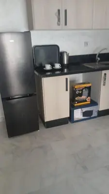 a kitchen with a refrigerator and a counter top at Relaxing Studio Stay with Pool, Balcony & Smart TV in Aïn Harrouda