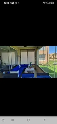 a living room with blue chairs and a table at Appartement en front de mer in Sidi el Haj Bou Derbala