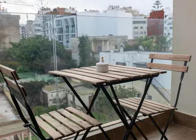 a wooden table and two chairs in front of a window at Studio Joudia in Casablanca