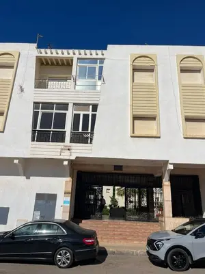 a black car parked in front of a building at Appartement lumineux en plein coeur de harhoura in El Harhoura