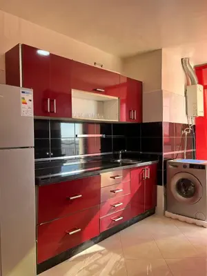 a kitchen with red cabinets and a washing machine at Appartement lumineux en plein coeur de harhoura in El Harhoura