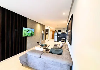 a living room with a couch and a tv on a wall at Grand Studio Moderne au Centre, Parking Privé in Casablanca