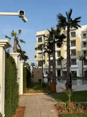 a building with palm trees in front of it at appartement de Lux le clos in Bouznika
