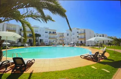 a large swimming pool with chairs and umbrellas at Appartement al yakout 1 in Mansouria