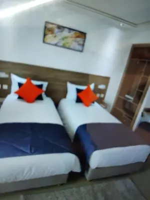 two beds in a hotel room with red pillows at Belle chambre pour 2 sidi maarouf HOTEL in Casablanca